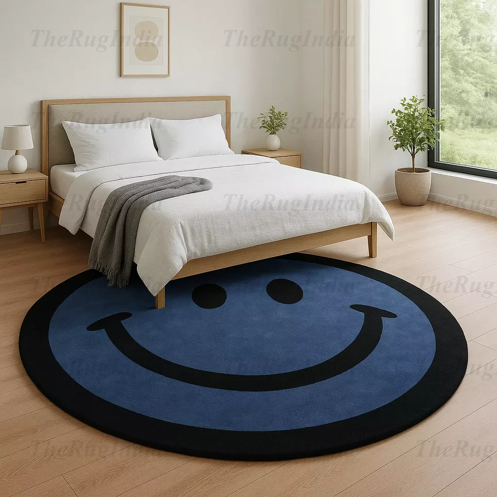 Hand-tufted round blue rug with black smiley face, placed in a modern living room with light wood flooring and minimalist chairs.